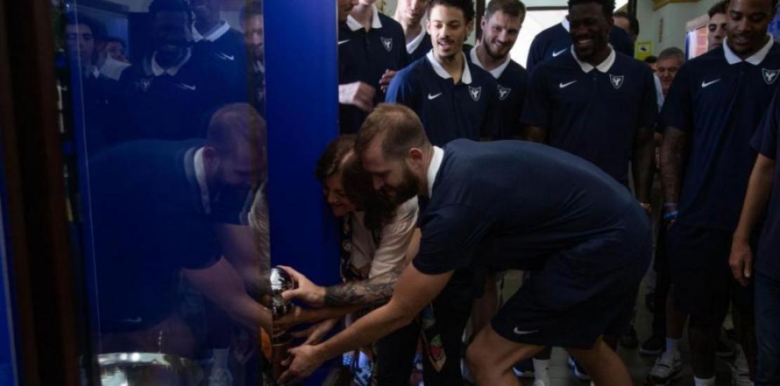 María Dolores García, president of UCAM and UCAM Murcia CB, and Nemanja Radovic, captain of the team, place the cup in the UCAM trophy cabinet