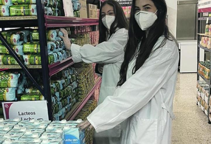 Two BBA students collaborating with Cáritas Diocesana in the San Antón Commissary.